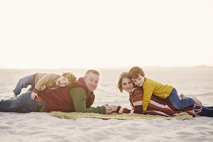 brother and their parents on the beach in earthy colors