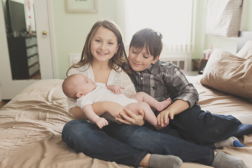 Oceanside Big Sister and brother holding newborn