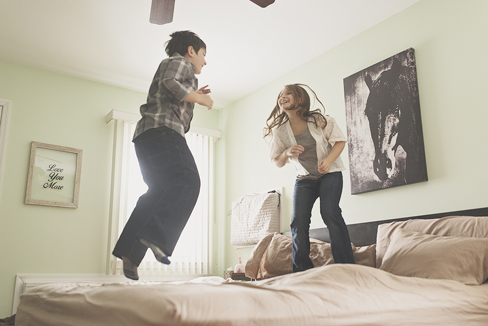 Long Island brother and sister jumping on bed