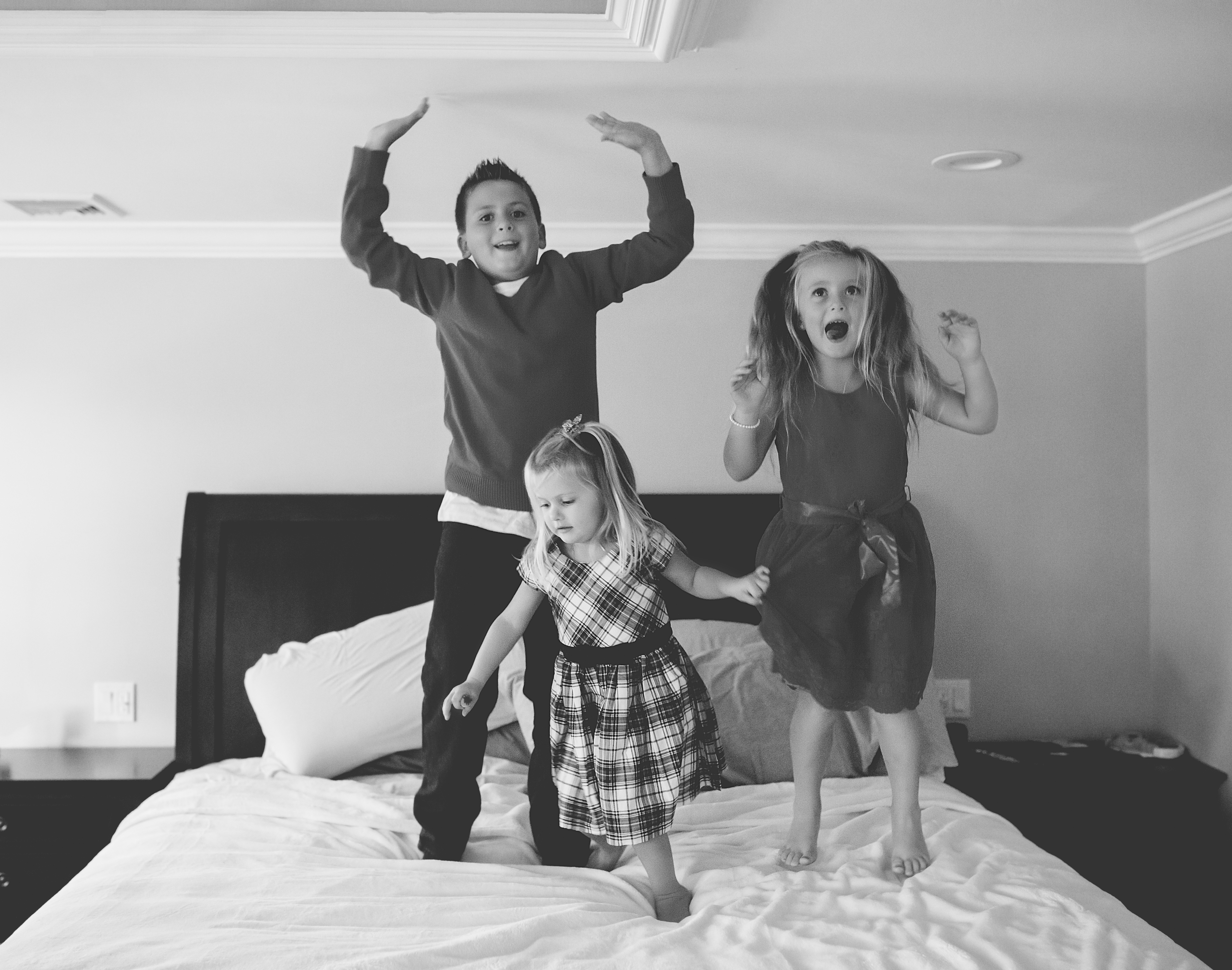 kids jumping on the bed in black and white