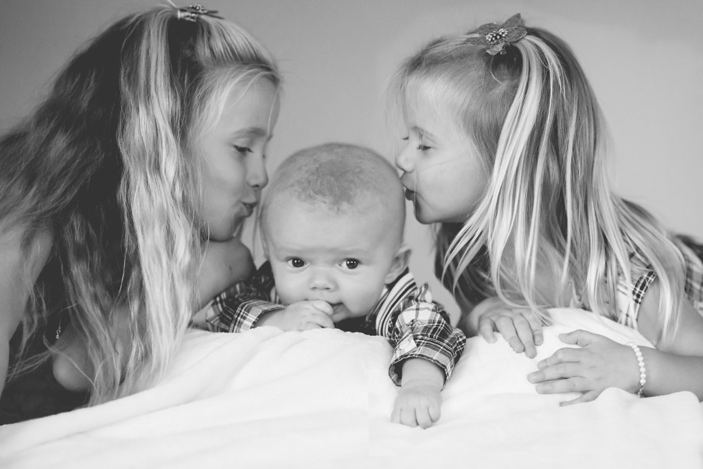 sisters kissing baby brother