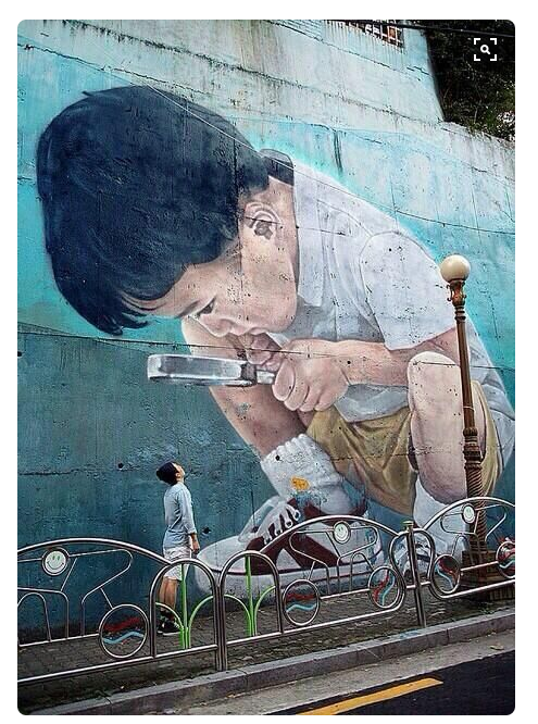 Boy looking through magnifying glass street art