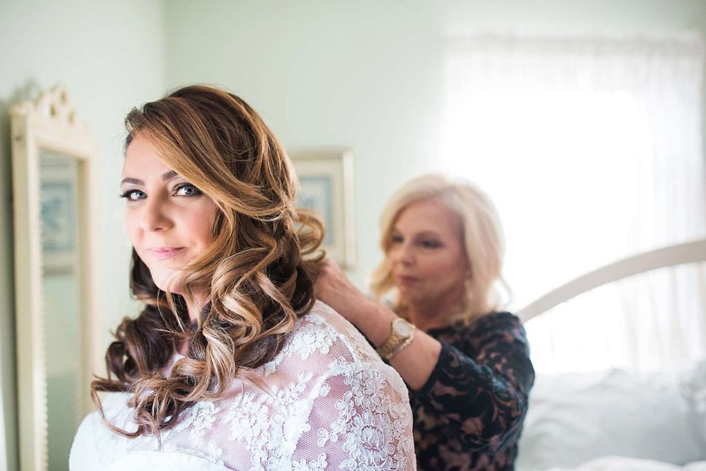 Long Island Wedding Photographer mom zips bride's dress