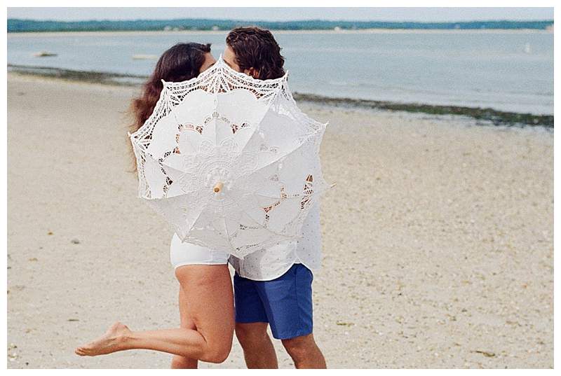 Long Island Film Beach Engagement romantic couple kissing behind paresol