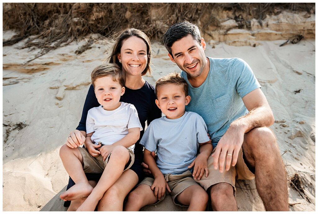 little boys on the beach with mom and dad cuddle